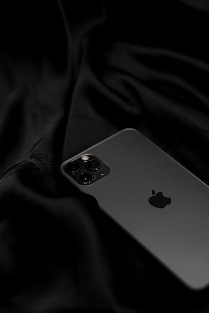 Stylish black smartphone on sleek satin fabric, showcasing modern technology design.