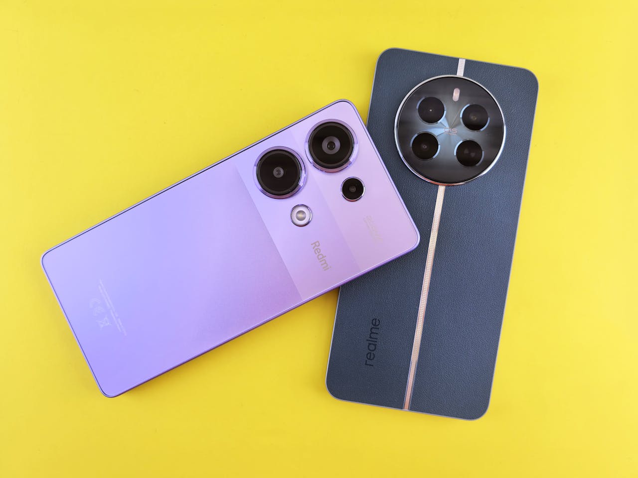 Top view of Redmi and Realme smartphones on a bright yellow background, highlighting modern design.